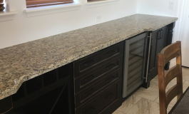 In-home bar completed with distressed finished cabinetry topped with a granite countertop. Dedicated space for wine and beverages, with an abundance of prep area. (Location: Goodyear, AZ)
