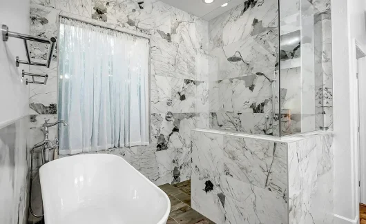 This master bathroom features a bold shower with Quartzite Patagonia porcelain wall tile and a free-standing soaking tub, creating a luxurious, spa-like retreat.